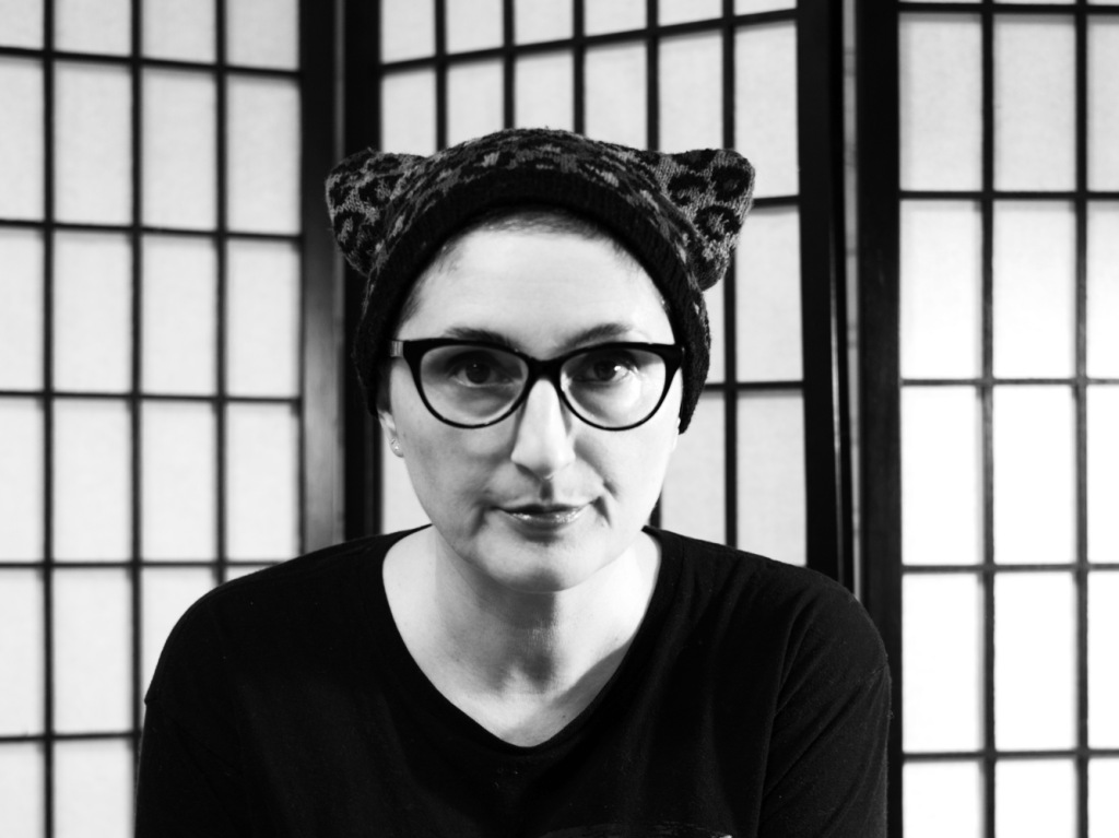 A black and white portrait of Kephren wearing a leopard spotted cat ear hat