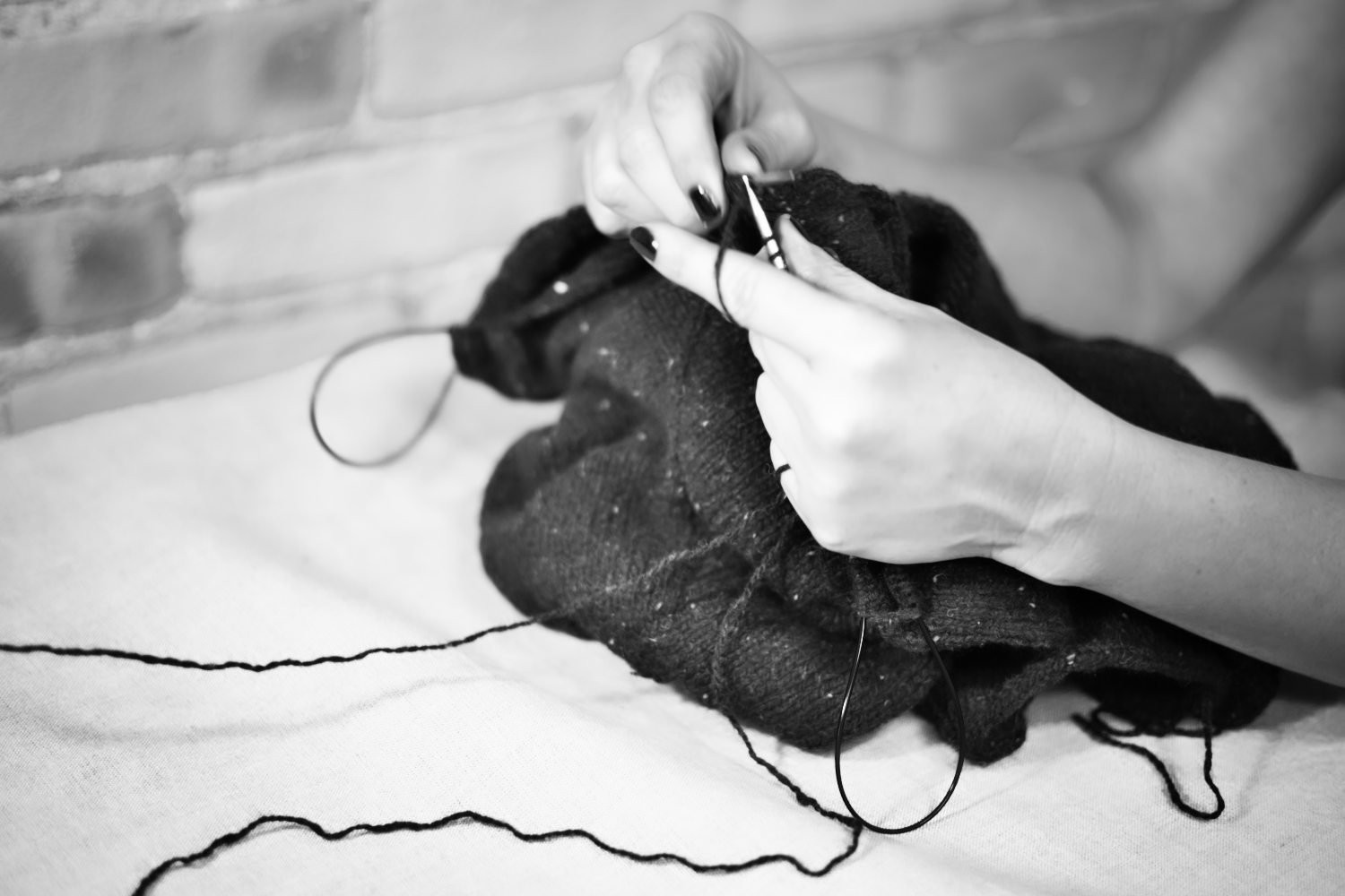 A black and white photo of hands knitting